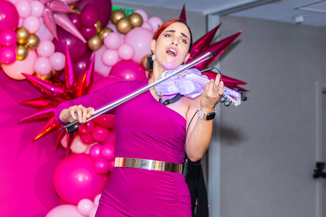 A violinist performing in front of the pink balloon wall