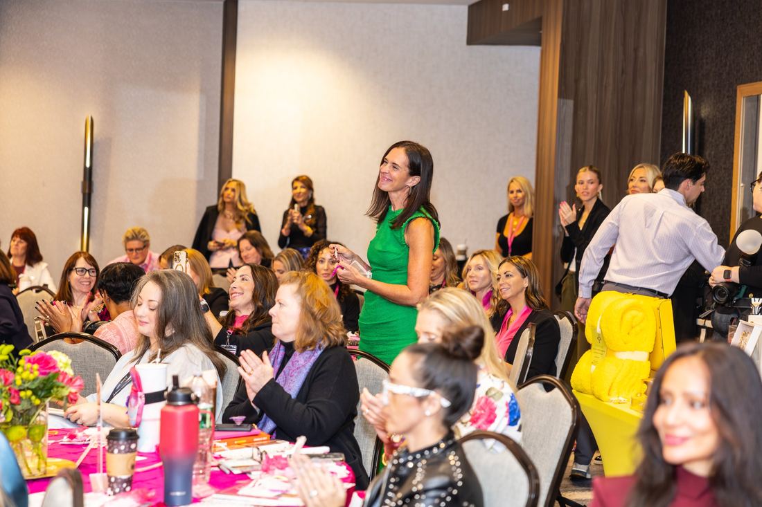 Attendees applauding as a woman stands at her table