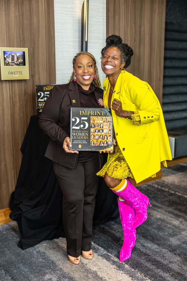 Two attendees holding a copy of IMPRINT