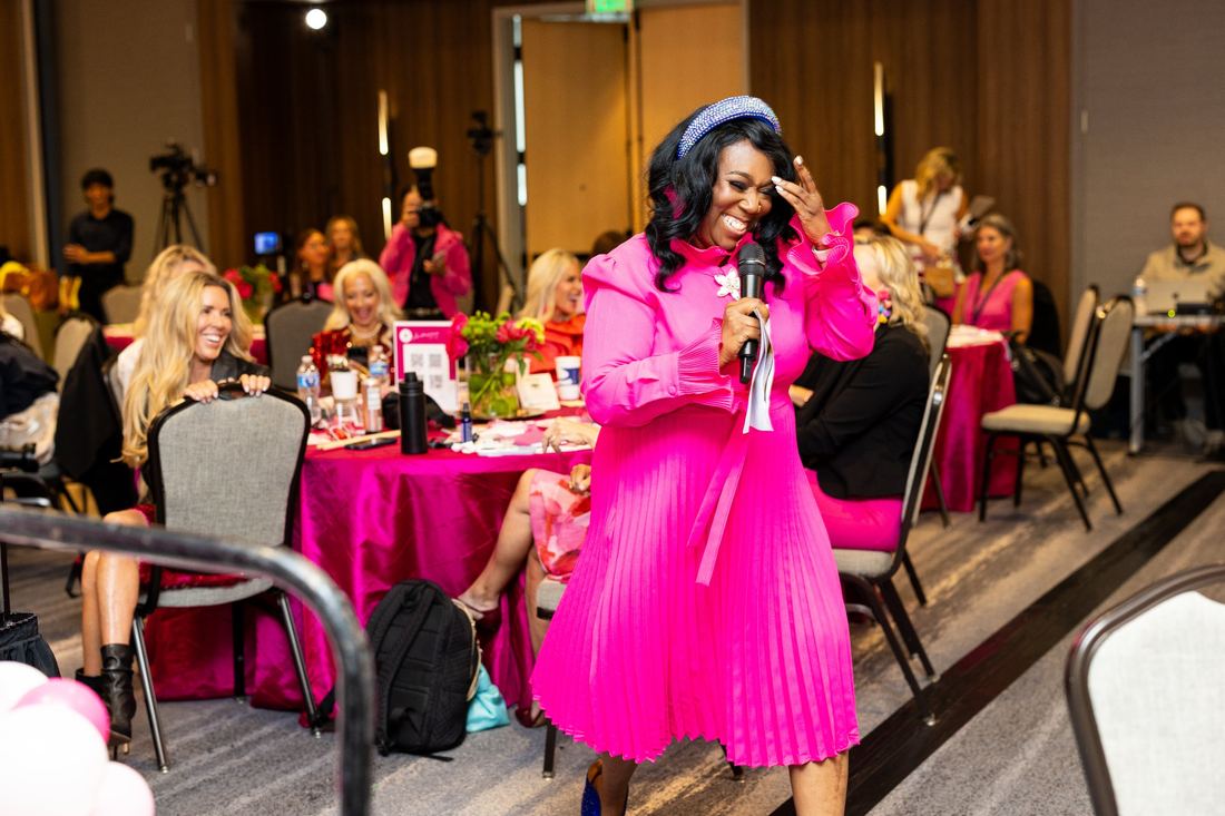 The emcee laughing as she walks between the tables