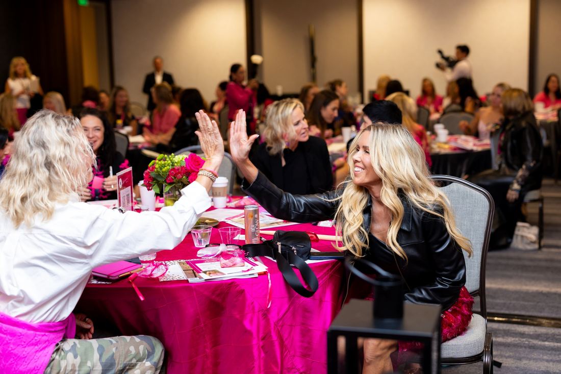 Two attendees high-fiving at their table
