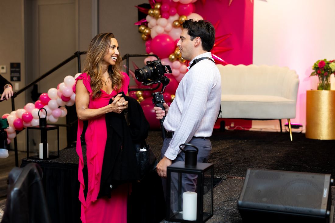 A speaker interviewed on camera beside the stage